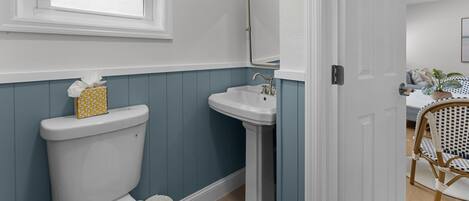 A bathroom with a toilet, sink, and window.