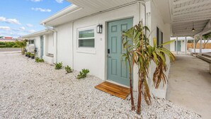 A single-story building with a light blue door, a small window, and a number '13' on the wall. - Tidal Wave Oceanfront Hideaway (Cocoa Beach)