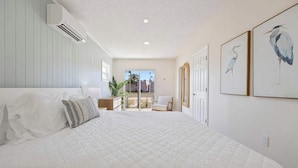Un dormitorio con una cama grande, una silla y vistas al exterior.
