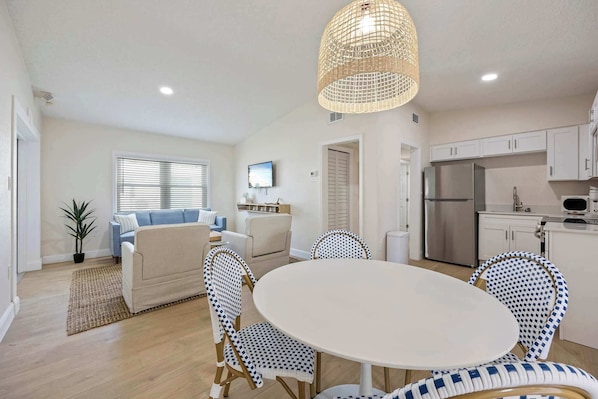 A modern kitchen with white cabinets, a stainless steel refrigerator, and a microwave.