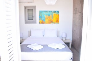 A neatly made bed with white linens, a bedside table with a lamp, and a wooden wardrobe. - Villa Ariadne, Divine Sea Views, Private Pool, Furnished Terrace, Andros (Andros)