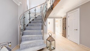 A staircase with a glass railing, a lantern, and a door in a hallway. - Luxury Sea View House | Whitstable Beachfront (Seasalter)