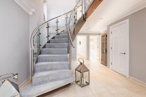 Eine Treppe mit Glasgeländer, einer Laterne und einer Tür in einem Flur.