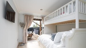 A bunk bed room with a TV, curtains, and a view of the outside. - Luxury Sea View House | Whitstable Beachfront (Seasalter)
