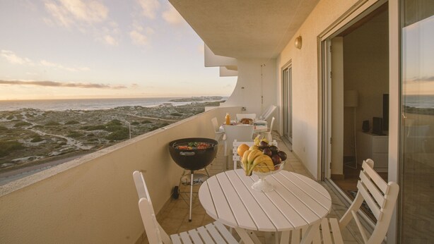 A balcony with a table, chairs, a grill, and a bowl of fruit. - Best Houses 64 - Sunset Beach (Baleal)