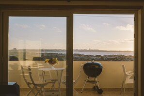 Ein Balkon mit Grill, Tisch und Stühlen und Meerblick.