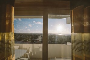 Ein Balkon mit Blick auf das Meer und eine entfernte Stadt.
