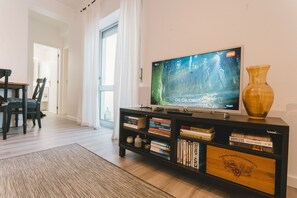 Ein Wohnzimmer mit Fernseher, Büchern und einer Vase auf einem Regal.