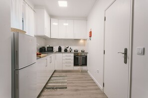 Eine moderne Küche mit weißen Schränken, einem Kühlschrank, einer Mikrowelle, einem Herd und einem Spülbecken.