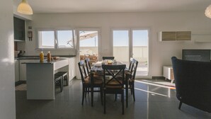 Eine moderne Küche mit Essbereich, großen Fenstern und Blick ins Freie.