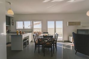 Eine moderne Küche mit Essbereich, großen Fenstern und Blick ins Freie.
