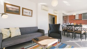 Ein Wohnzimmer mit Sofa, Sessel, Couchtisch und einem Essbereich mit Stühlen und Tisch.