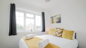 A hotel room with a bed, a window, and a painting on the wall. - Spacious 4 Bedroom Home With Free Parking (Northampton)