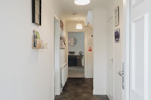 A hallway with a radiator, a door, and a wall-mounted light fixture. - Spacious 4 Bedroom Home With Free Parking (Northampton)