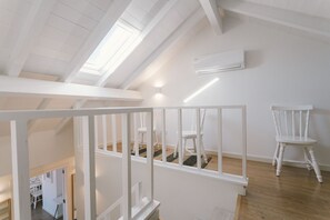 Ein geräumiges Loft mit hohen Decken, einem Oberlicht, weißen Wänden und Holzboden.