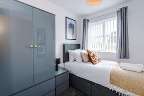 A bedroom with a bed, a wardrobe, a nightstand, and a window with curtains. - Stylish 2 BDR APT Free Parking Liverpool (Liverpool)