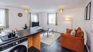 Una cocina moderna con lavadora, un comedor con mesa y sillas, y una sala de estar con sofá.