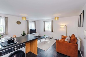 A modern kitchen with a washing machine, a dining area with a table and chairs, and a living area with a sofa. - Stylish 2 BDR APT Free Parking Liverpool (Liverpool)