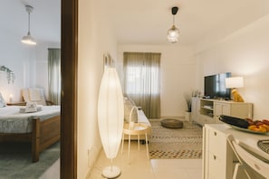 A modern living room with a sofa, TV, and a dining area with a table and chairs. - Best Houses 32 - Dunas Beach Peniche (Peniche)