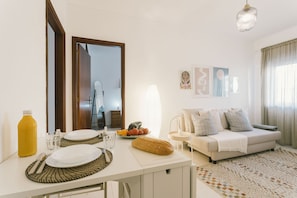 A dining area with a table set for two, a sofa, and a mirror. - Best Houses 32 - Dunas Beach Peniche (Peniche)