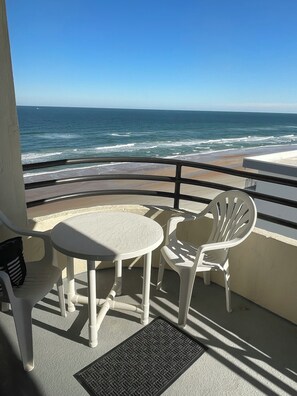 A balcony with a table and two chairs, overlooking the ocean. - Sand Dollar Condo Unit 904 Pool and Beach Access are now Open (Daytona Beach Shores)