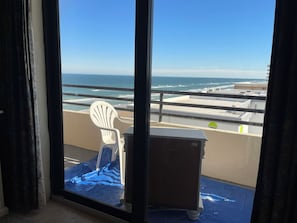 A balcony with a white chair, a small table, and a view of the ocean. - Sand Dollar Condo Unit 904 Pool and Beach Access are now Open (Daytona Beach Shores)