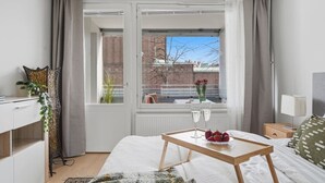 A bedroom with a bed, bedside table, and a window with curtains. - Home Spa | Balcony | EV Parking | 200m Tram | 3BR (Helsinki)