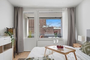 A bedroom with a bed, bedside table, and a window with curtains. - Home Spa | Balcony | EV Parking | 200m Tram | 3BR (Helsinki)