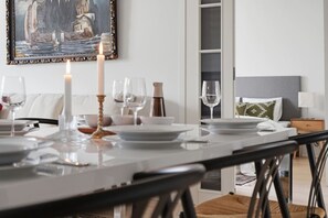 Un comedor con una mesa dispuesta para dos personas, una vela y un cuadro en la pared.