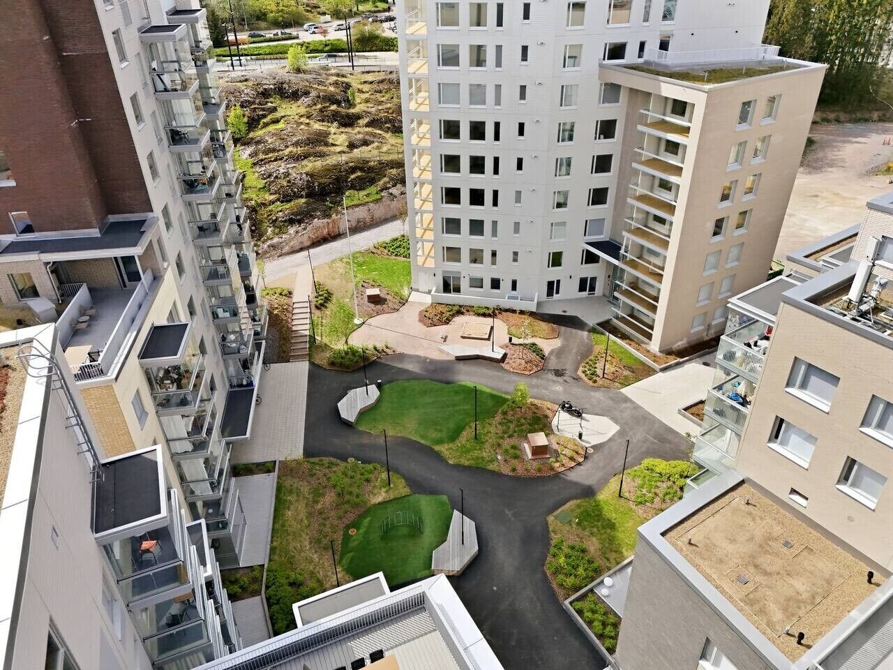 A high-rise residential building with multiple balconies, a central courtyard with greenery, and a parking area.