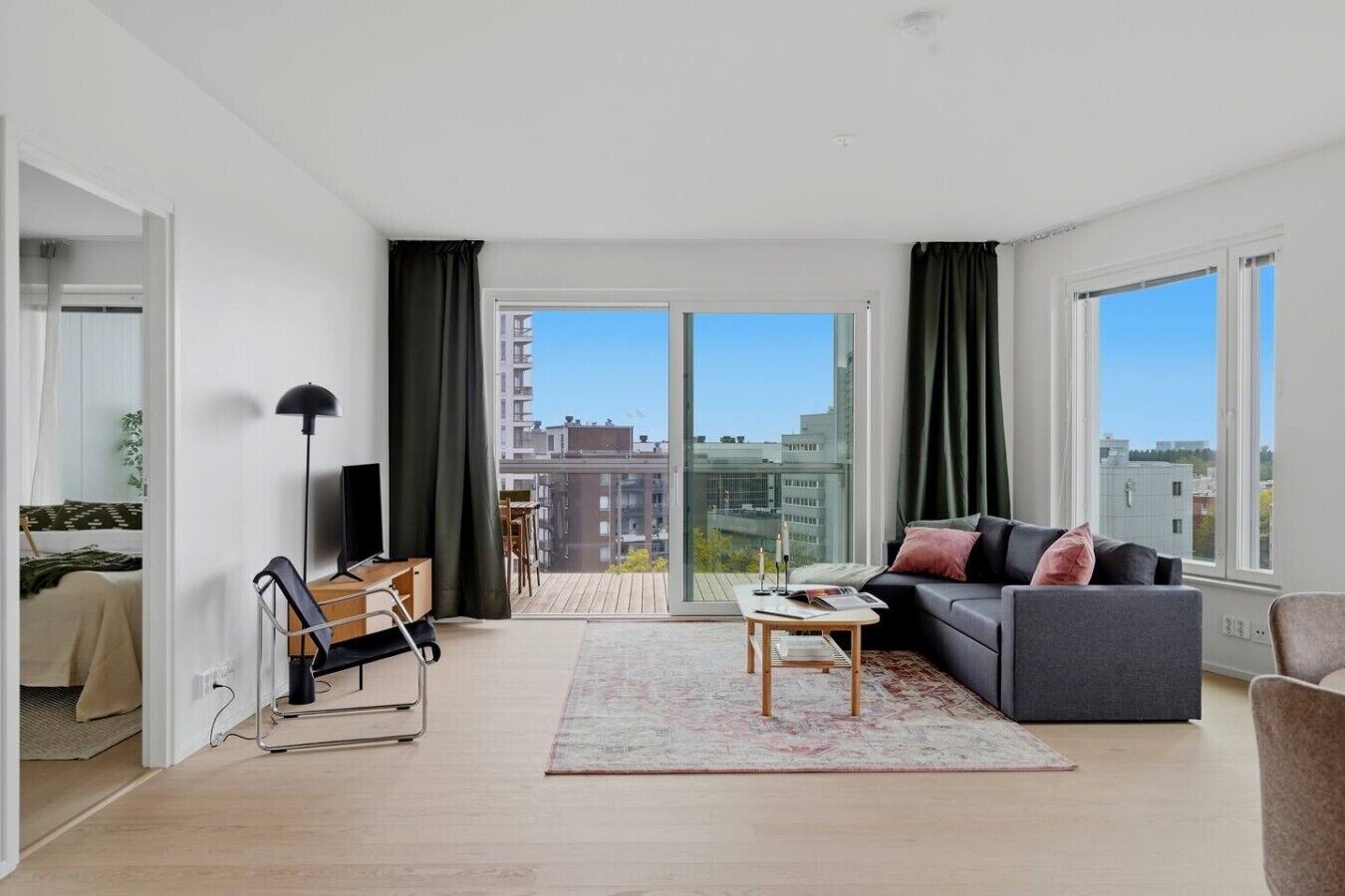 A modern living room with a sofa, coffee table, and a view of the city through large windows.