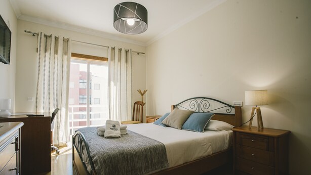 Un dormitorio con cama, mesitas de noche, lámpara, escritorio y silla.