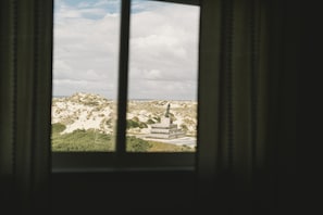 Blick aus einem Fenster auf eine Wüstenlandschaft mit einer Statue.