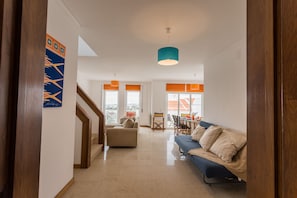 Ein modernes Wohnzimmer mit Sofa, Esstisch und Treppe.