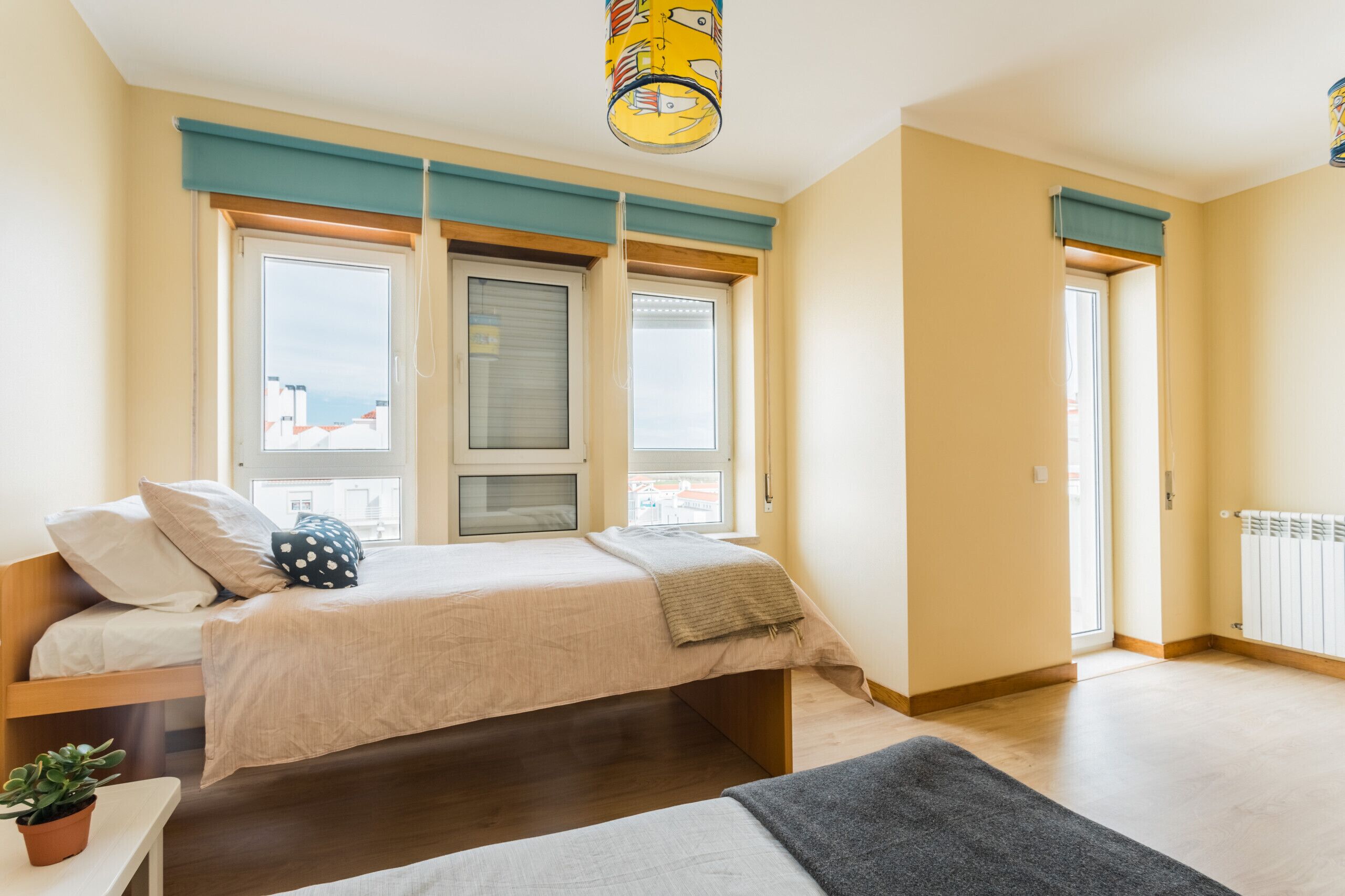 Ein Schlafzimmer mit einem Bett, einem Fenster, einer Heizung und einer Topfpflanze.