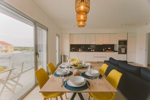 A modern dining area with a table set for four, yellow chairs, and a view of the city through large windows. - Best Houses 25 - Seaside Retreat (Consolação)