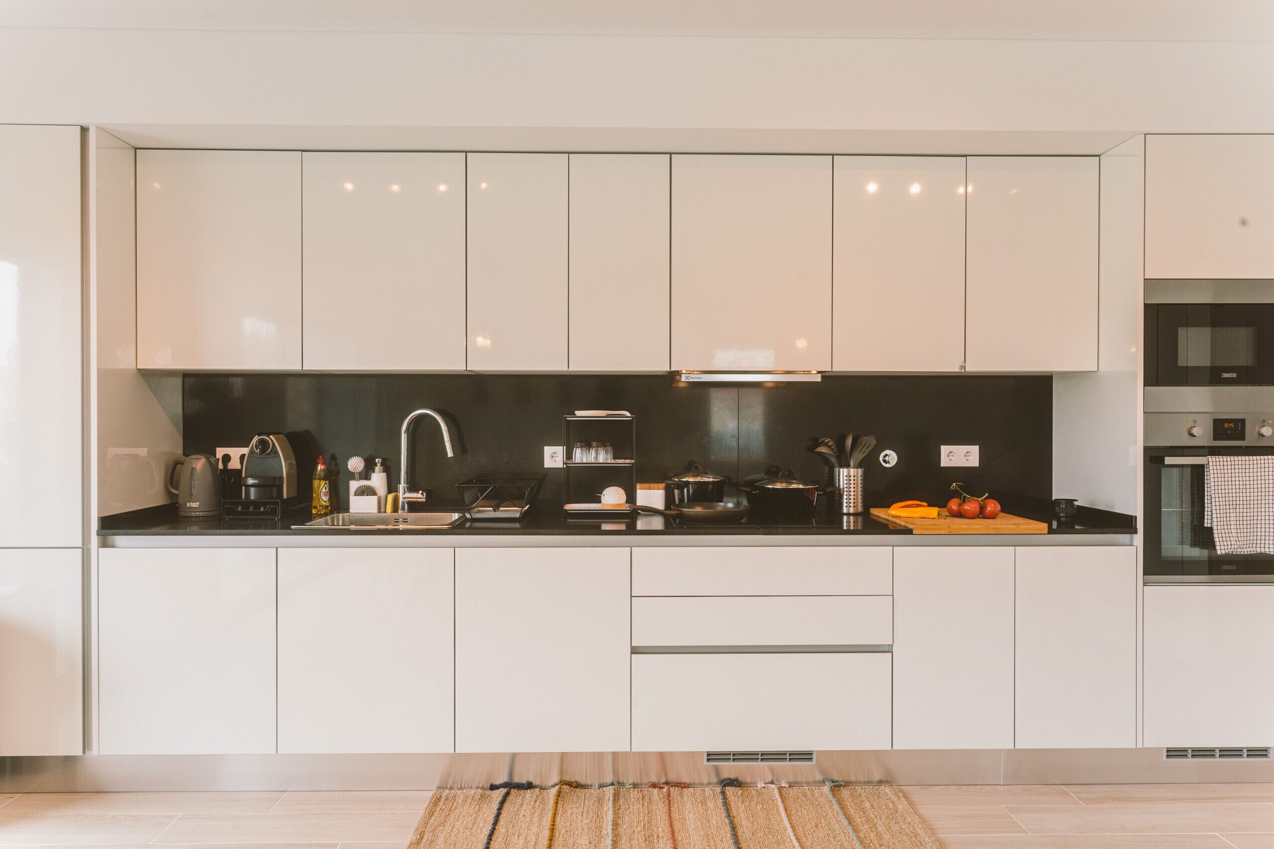 Een moderne keuken met witte kastjes, een zwart aanrecht en een ingebouwde oven.