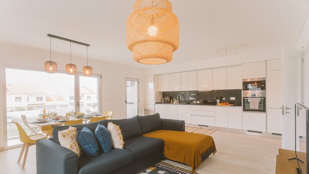 En moderne opholdsstue med sofa, spisebord og køkkenområde.
