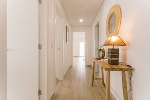 A hallway with a wooden console table, a wall-mounted mirror, and a lamp. - Best Houses 25 - Seaside Retreat (Consolação)