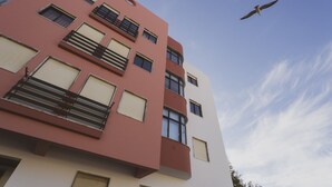 Een meerlaags gebouw met balkons, grote ramen en een heldere lucht.