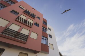 Ein mehrstöckiges Gebäude mit Balkonen, großen Fenstern und blauem Himmel.