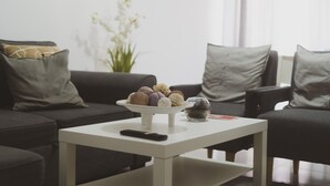 Een woonkamer met een witte salontafel, een afstandsbediening en een schaal met lekkernijen.