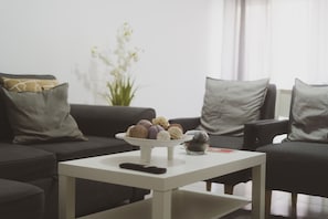 Ein Wohnzimmer mit einem weißen Couchtisch, einer Fernbedienung und einer Schüssel mit Snacks.