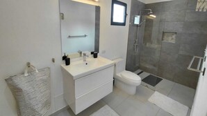 Een moderne badkamer met een wastafel, spiegel en douche.