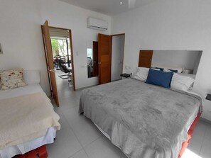 A bedroom with a large bed, a smaller bed, a mirror, and a door leading to a bathroom. - Charming 1-bedroom apartment with AC in Las Terrenas - LAS BAELLENAS (Las Terrenas)
