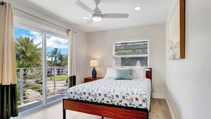 A bedroom with a bed, a ceiling fan, a window with blinds, a nightstand, and a view of the outdoors. - Delray Beach Paradise - Downtown Atlantic Ave (Delray Beach)