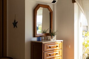 A wooden dresser with a mirror above it, a star decoration on the wall, and a potted plant on the dresser. - Best Houses 36 - Baleal Surf Village (Baleal)