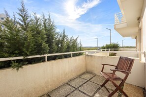 A balcony with a chair, a railing, and a view of trees and a distant landscape. - Best Houses 36 - Baleal Surf Village (Baleal)