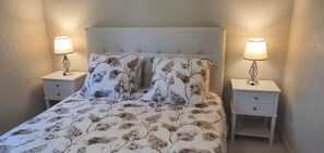 A bed with floral bedding, two bedside tables with lamps, and a headboard.