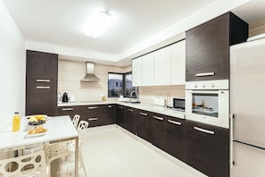 A modern kitchen with dark cabinetry, a white countertop, and a built-in oven. - Best Houses 23 - Surf & Chill Apartment Baleal (Ferrel)